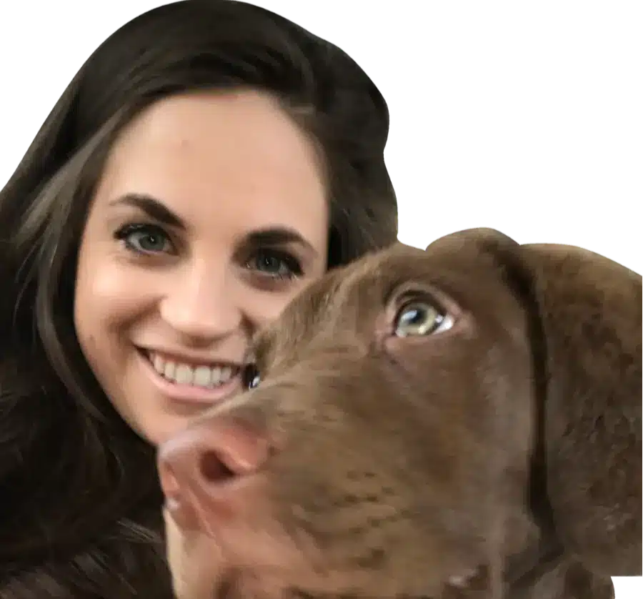 Smiling woman with long dark hair and a close-up brown dog whose face fills the foreground, the dog looking upward